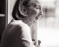 Happy old woman looking out window
