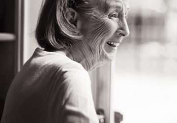 Happy old woman looking out window