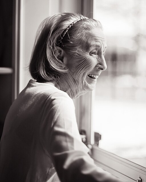 Happy old woman looking out window