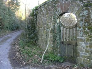 Closed wooden gate in a stone wall by a road.
